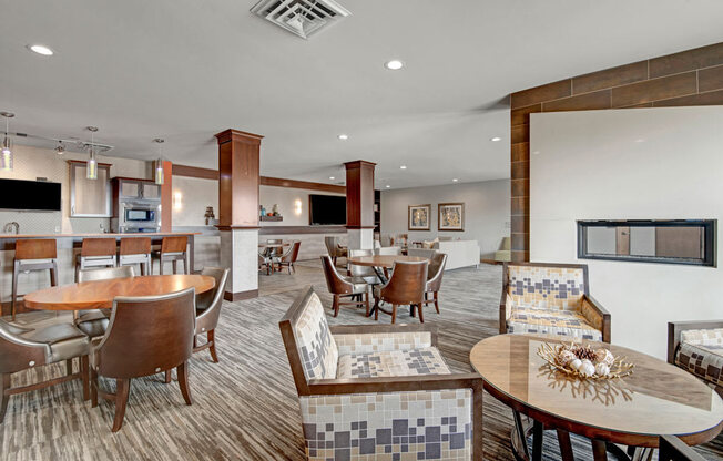A welcoming clubhouse lounge here at Vue at Pinnacle Park with dining tables and chairs, a modern fireplace wall, bar-height seating, pendant lighting, and open social areas designed for relaxing and community gatherings.