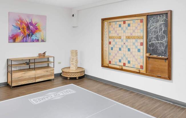 A room with a large painting, a chess board, and a chalkboard on the wall.