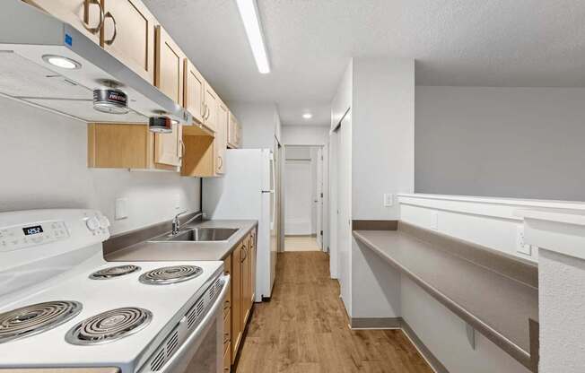 A kitchen with a white stove top oven and a white dishwasher.
