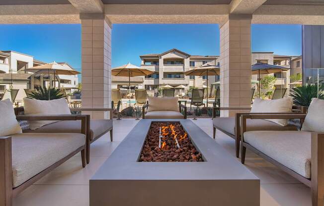 A modern outdoor seating area with a fire pit in the middle.