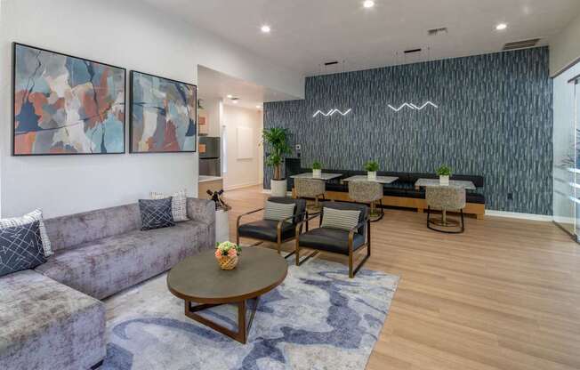 A living room with a grey couch, a coffee table, and two chairs.