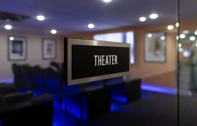 a theater room with a sign for theater on a glass wall