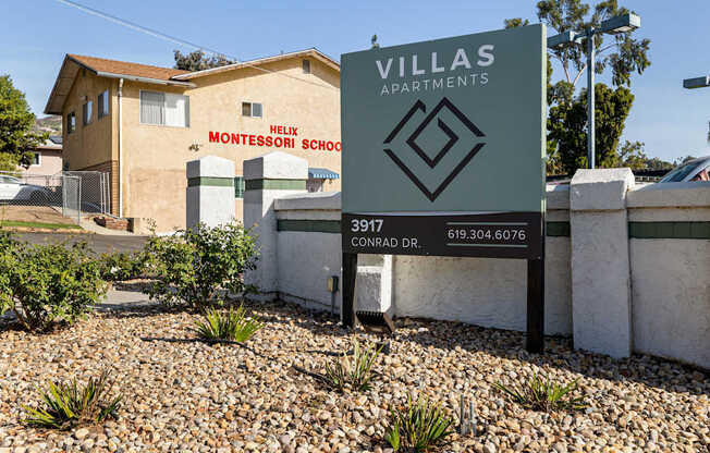 A sign for Villas Apartments stands in front of a building with a Montessori school.