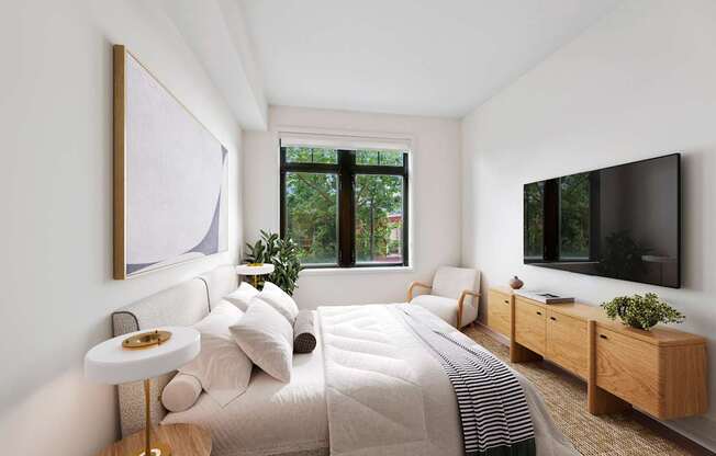 A modern bedroom with a large bed, a TV, and a window with a view of trees.