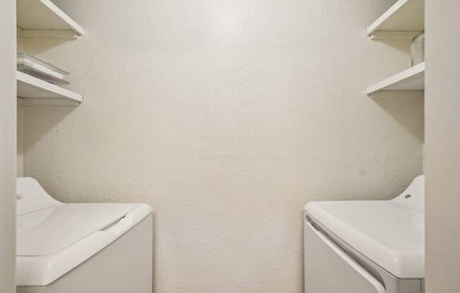 Two white washing machines in a laundry room.