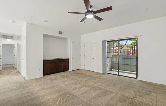A room with a ceiling fan and carpeted floor.
