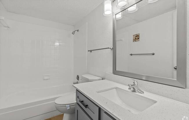A white bathroom with a toilet, sink, and mirror.