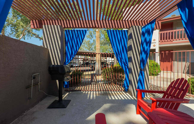 a patio with red chairs and blue and white curtains