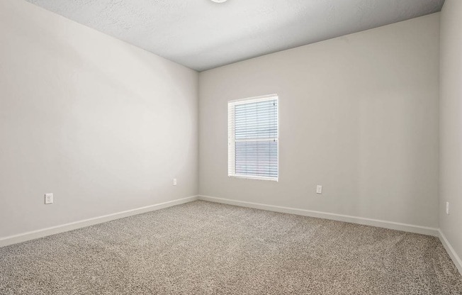 A room with a window and carpeted floor.