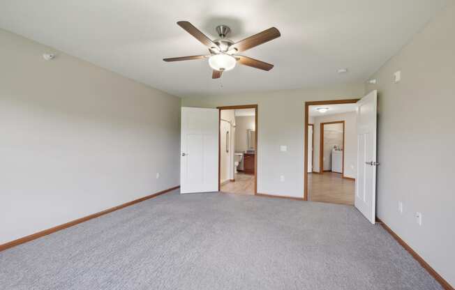 an empty living room with a ceiling fan and a carpet