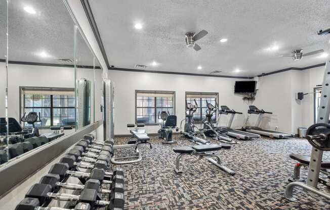 a spacious fitness center with cardio equipment and a flat screen tv