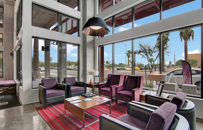 a lobby with purple chairs and a red rug
