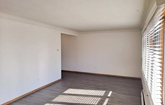 an empty living room with wood flooring and a window