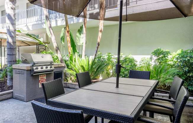 a patio with a table and chairs and a grill