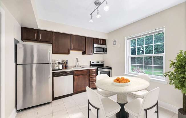 A kitchen with a table and chairs in front of a window.