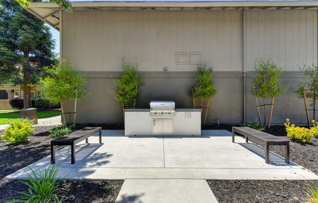 Exterior BBQ grill and courtyard with bench seating. area