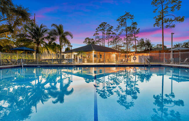 A pool with a building and trees in the background.