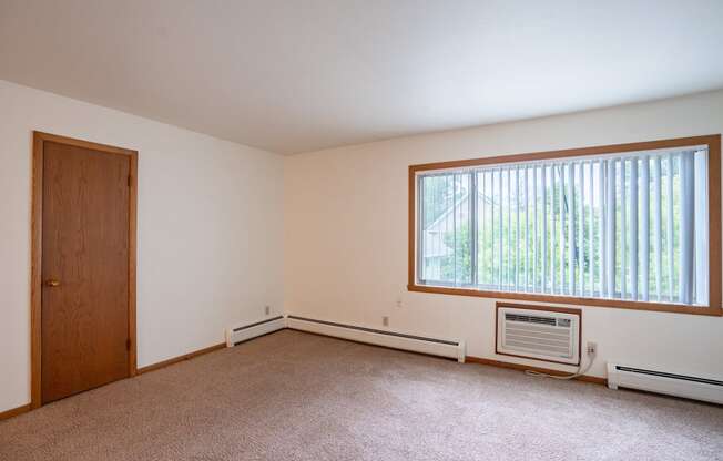 an empty living room with a large window and a door. Fargo, ND Crown Court 1 Apartments