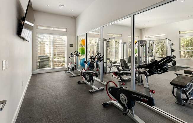 A gym with a mirrored wall and various exercise equipment.