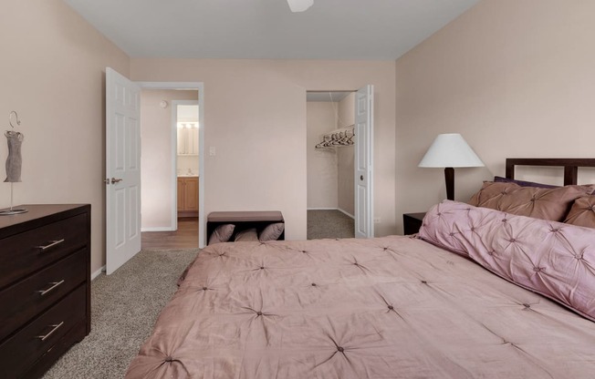 a bedroom with a bed and a dresser and a closet at St Charles Square Apartments, Carol Stream, IL, 60188