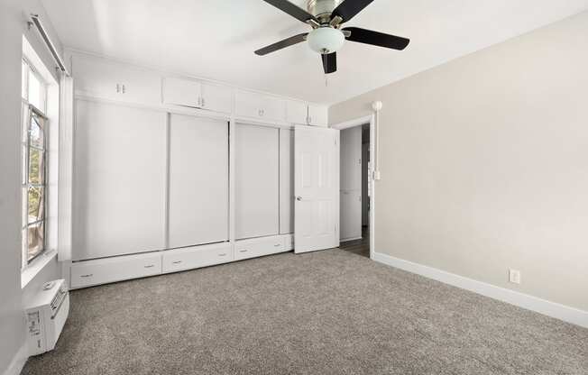 an empty room with white cabinets and a ceiling fan