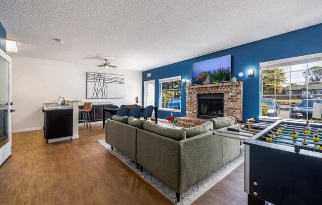 A living room with a grey couch, a fireplace, and a foosball table.