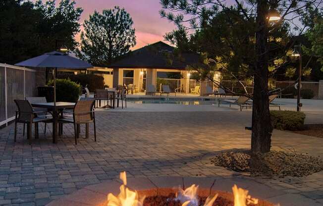 a fire pit in front of a pool at night