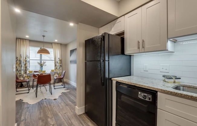 the kitchen and dining room of a home with a black refrigerator