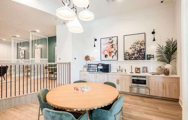 A kitchen with a table and chairs in the foreground and a woman standing in the background.