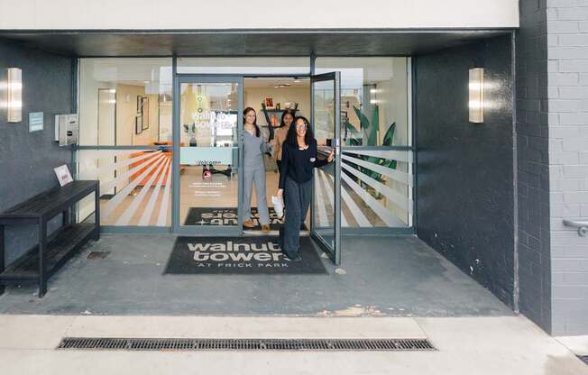 Two women standing in front of a glass door with a sign that says "Walnut Tower at Trick Park".