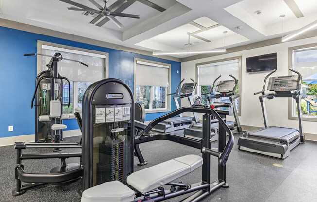 A gym with a variety of equipment including treadmills, elliptical machines, and a rowing machine.