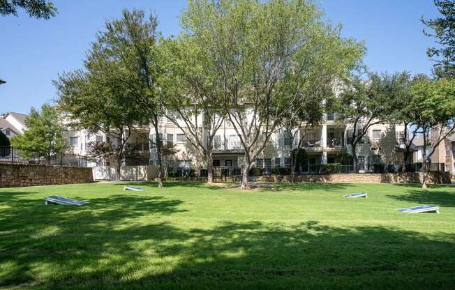 a grassy area with trees in front of a building