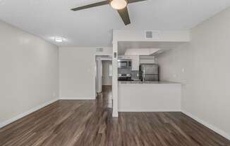 an empty living room and kitchen with a ceiling fan