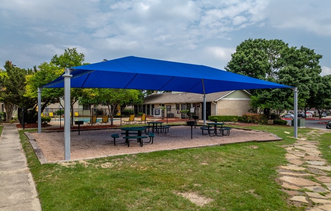 a blue pavilion with picnic tables under it      in front