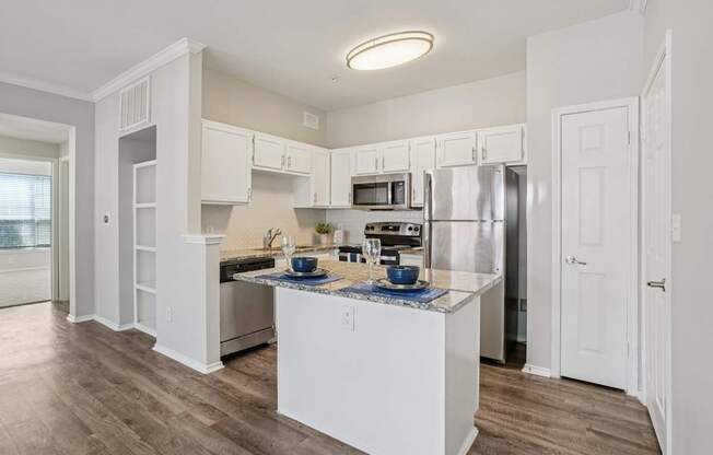 A kitchen with white cabinets and a wooden floor.