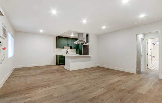 a living room and kitchen with white walls and wood floors