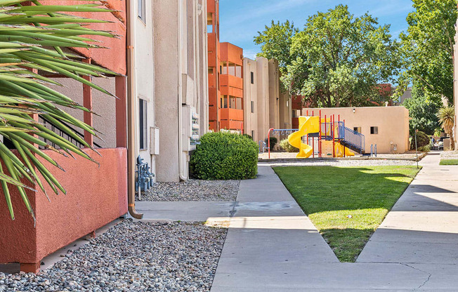 a sidewalk leading to an apartment building with a yellow slide in the background