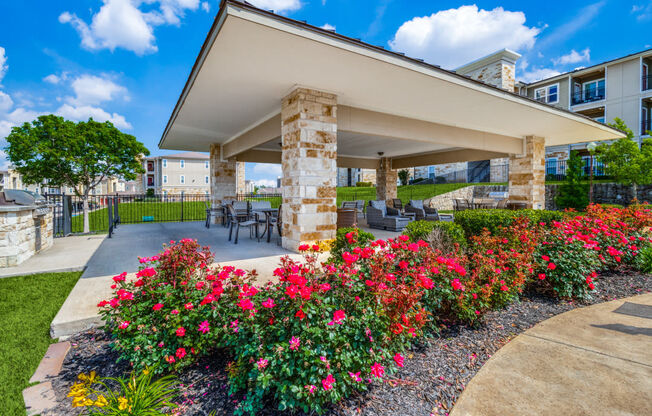 a patio with flowers and a table and chairs in front of a building