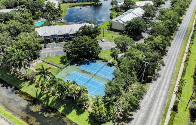 an aerial view of a tennis court and a house on a street