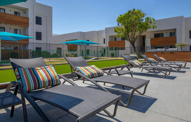 a row of chaise lounges with umbrellas in front of a building