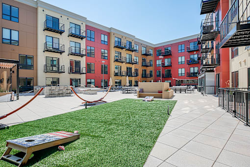 a courtyard with a hammock and a picnic table in front of an apartment building