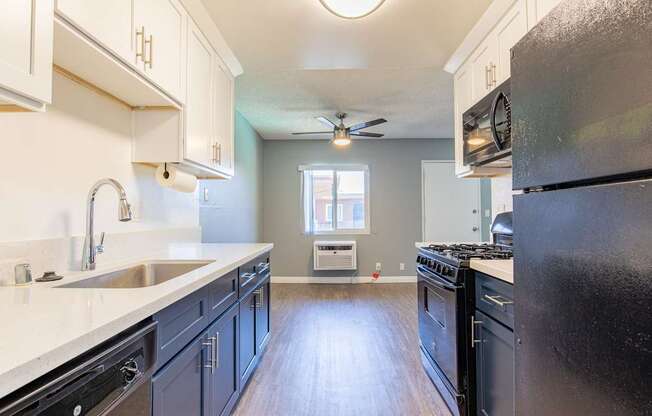 A kitchen with a black refrigerator and wooden floors.