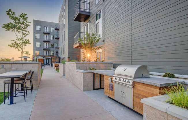 a patio with a grill and a table with chairs