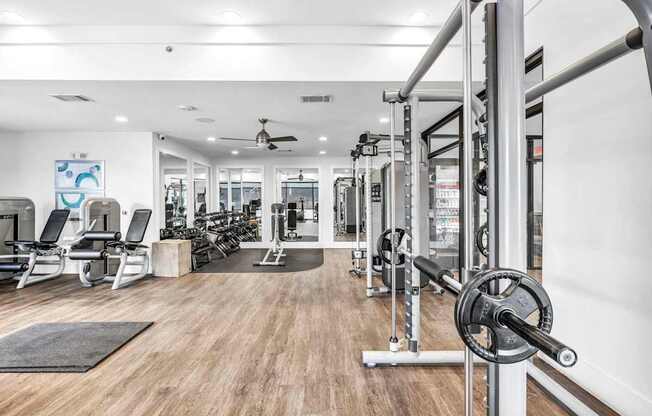 A gym with a variety of equipment including a squat rack, bench, and weights.