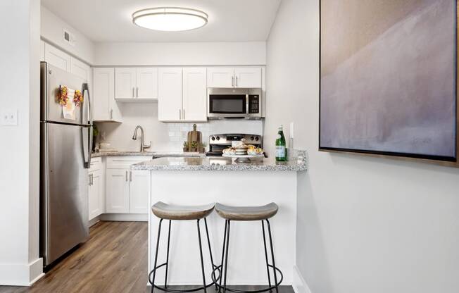 a kitchen with white cabinets and a small island with two stools at Linkhorn Bay Apartments, Virginia Beach