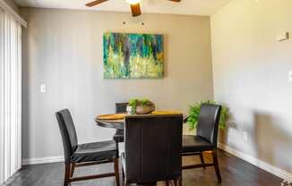 a dining room with a table and chairs and a painting on the wall