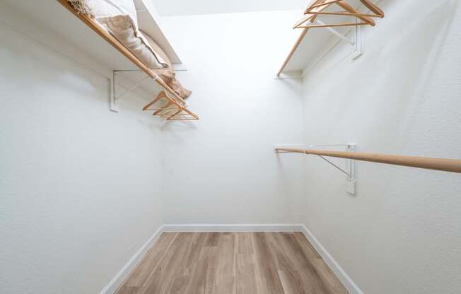 A hallway with a white wall and a wooden floor.