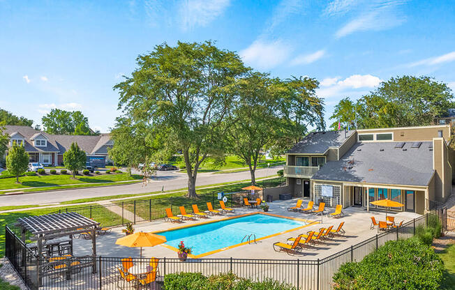 a swimming pool with chairs and umbrellas in front of a house