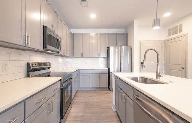 an empty kitchen with stainless steel appliances and white counter tops