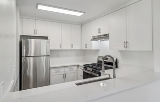 A modern kitchen with white cabinets and stainless steel appliances.